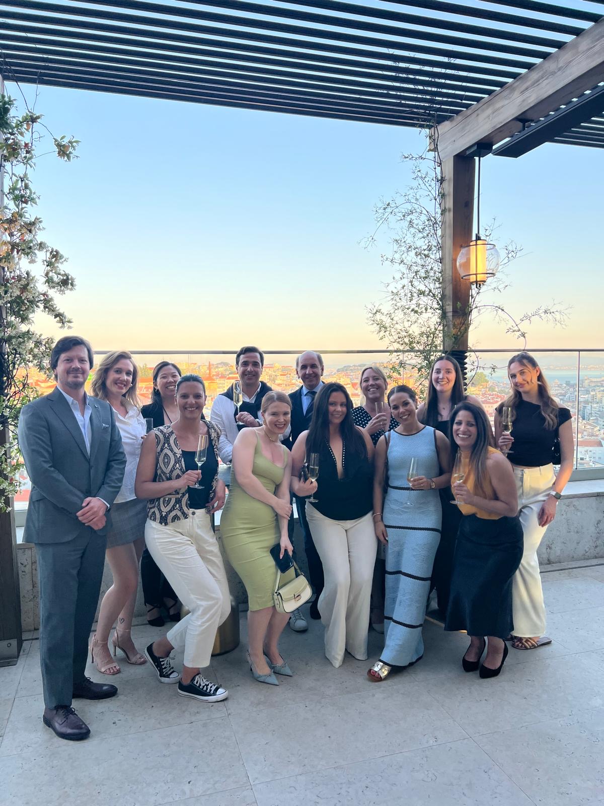 Cloud Nine Incentives team gathered on a pergola-covered rooftop bar in Lisbon at golden hour, with the city skyline behind them